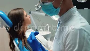 年轻的牙医戴着医用手套，戴着口罩，检查年轻的黑发女子`病人使用<strong>牙科器械</strong>的牙齿